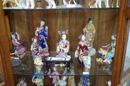Two shelves of modern glazed pottery Oriental figures, 16