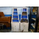 A pair of white painted book cases with cupboard below