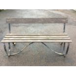 A 5ft wrought iron garden bench with batton back and slatted seat raised on shaped scrolled legs