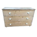 A Victorian pine chest of three long drawers mounted with white glazed porcelain knobs. (52in x 18.