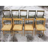 A set of four folding beech framed chairs with cane seats; and another stained set of five with