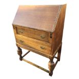 An oak bureau with fallfront enclosing an interior with pigeonholes, the desk with two long