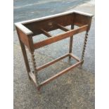 A oak stickstand with three divisions raised on barleytwist supports joined by rectangular