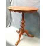 A circular Victorian ash occasional table with moulded top above a scalloped apron, raised on a
