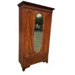 An Edwardian mahogany wardrobe with moulded cornice above an oval bevelled mirror door flanked by
