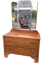 An oak dressing table with easel mirror to top flanked by hinged wings, the chest with two long