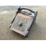A Victorian carved oak coal scuttle, the angled hinged lid with lionhead framed by scrolling, having