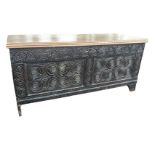 An antique carved oak coffer with later rectangular moulded top, the front carved with two
