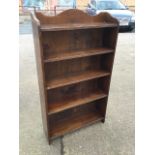 A small oak open bookcase with shaped moulded back above five shelves. (24in x 6.5in x 43in)