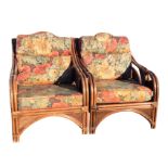 A pair of cane framed conservatory armchairs with floral upholstered loose cushions, the sides and