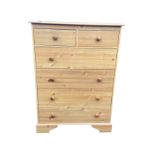 A Victorian style faux-pine chest of drawers, with two short and four long knobbed drawers, raised