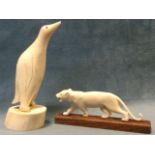 A walrus tusk carved as a penguin on column stand; and a carved tiger mounted on a rectangular