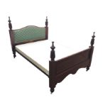 A mahogany double bed with arched upholstered headboard, the cornerposts with leaf carved bands