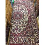An oriental style rug woven with oval floral panel on fawn ground framed by red scrolled