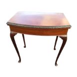 A bowfronted mahogany card table, the twin top with interior baize lining having ribbon carved