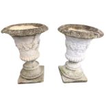 A pair of composition stone classical urns, with egg & dart moulded overhanging rims above foliate