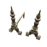 A pair of cast andirons, the columns with pointed finials on leaf scrolled supports, the back