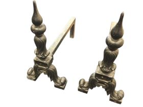 A pair of cast andirons, the columns with pointed finials on leaf scrolled supports, the back