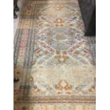 An antique oriental rug woven with three floral panels on fawn ground, having conforming border