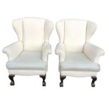 A pair of calico upholstered wing-back armchairs, with splayed flared arms and loose cushions to