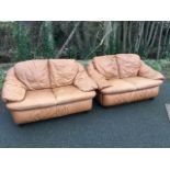 A pair of two-seater leather sofas with integral back, seat and armrest cushions, raised on