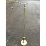 A brass standard lamp with circular switched weighted base supporting a column with scrolled leaf-