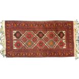 A Belouchi rug woven with field of serrated flowerhead medallions framed by hooked & scrolled