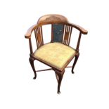 An Edwardian mahogany corner chair with scrolled leaf carving to back, having captains style