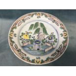 An eighteenth century English delft tin glazed charger decorated with tree and flowers with garden
