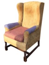 A Georgian style wingback armchair with shaped sides and padded arms above a sprung seat with an