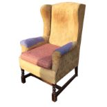 A Georgian style wingback armchair with shaped sides and padded arms above a sprung seat with an