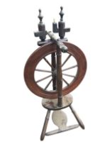 A nineteenth century mahogany spinning wheel with turned spindles raised above an oval platform with
