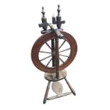 A nineteenth century mahogany spinning wheel with turned spindles raised above an oval platform with