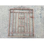 A rusty old wrought iron gate with scrolled decoration having vertical bars in rectangular frame