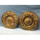 A pair of art nouveau style brass chargers with foliate scroll embossed rims, having central