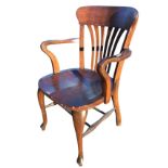 An Edwardian oak armchair with curved back rail above fan shaped slats, the crook arms above a solid