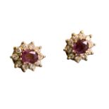 A pair of 18ct gold oval ruby earrings, each claw set stone framed by ten small diamonds, with