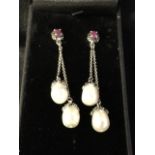 A pair of boxed silver, ruby and pearl drop earrings, the claw set oval ruby panels mounted with