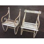 A pair of wrought iron painted garden armchairs with scrolled arms and slatted seats raised on