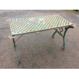 A rectangular cast iron garden table with an associated grid top, supported on scrolled ends with