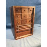 A hardwood collectors cabinet with nine small knobbed drawers above five slides fitted for coins,
