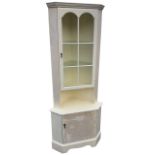 A painted corner cabinet with moulded cornice above twin arched astragal glazed door having open