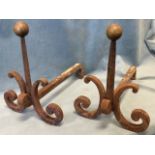 A pair of antique fire dogs with tapering scrolled wrought iron supports beneath square columns with