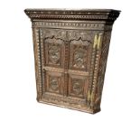 A Victorian carved oak corner cupboard with crescent carved dentil cornice above a leaf frieze and