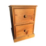 A pine filing cabinet with moulded top above two knobbed panelled drawers, raised on plinth. (18.5in