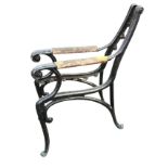 A pair of painted cast iron bench ends with integral wood armrests, raised on scrolled supports. (