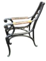 A pair of painted cast iron bench ends with integral wood armrests, raised on scrolled supports. (