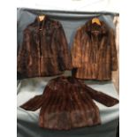 A ladies fur coat of hip length with stand up collar, shoulder pads, hook and eye fastenings and