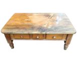 A rectangular pine coffee table, the rounded top above a deep apron containing three knobbed