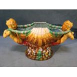 A majolica glazed shell vase flanked by mermaid type figures holding rope foliage, raised on an oval